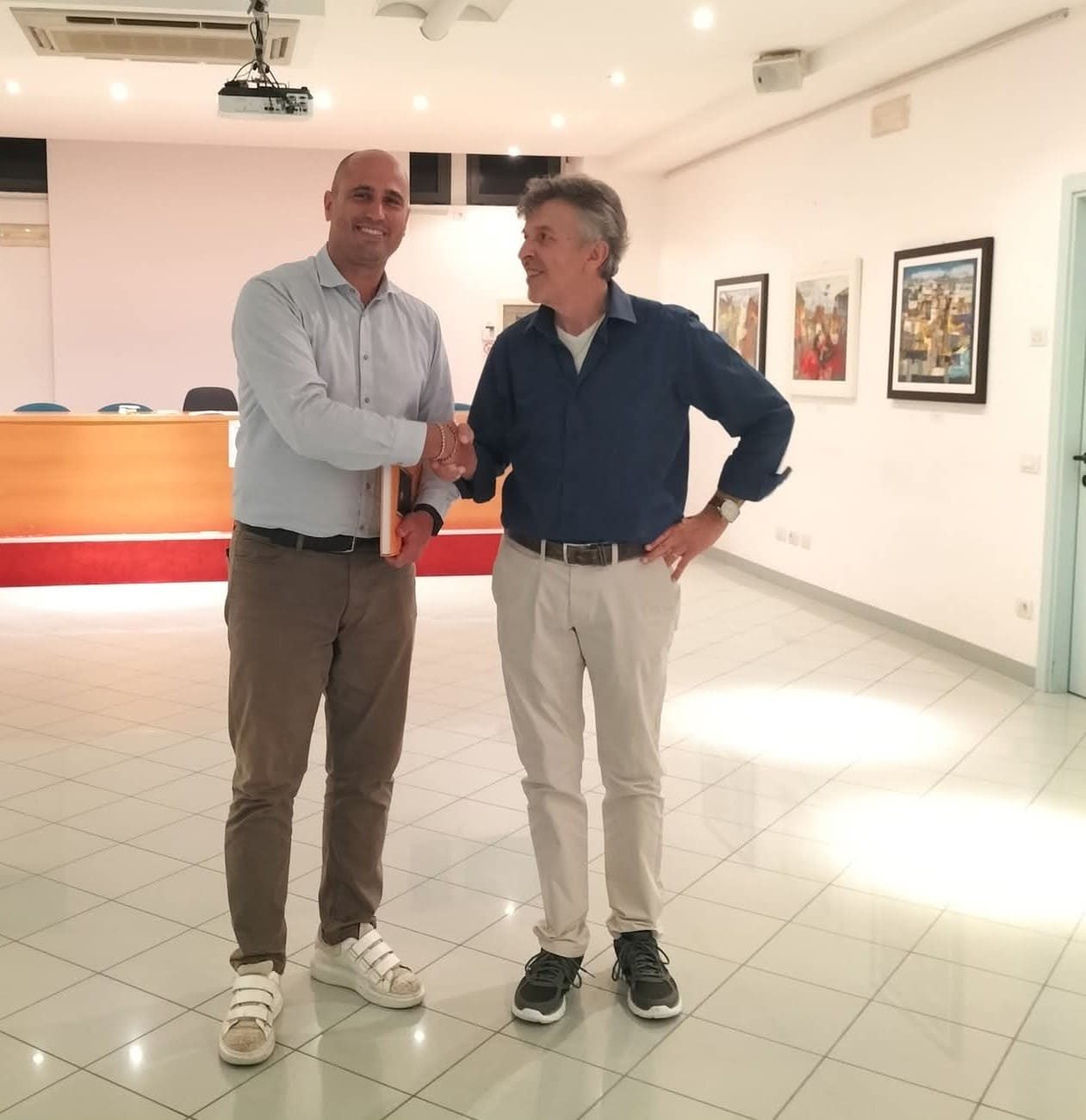 L'artista stringe la mano a un ospite nella sala espositiva