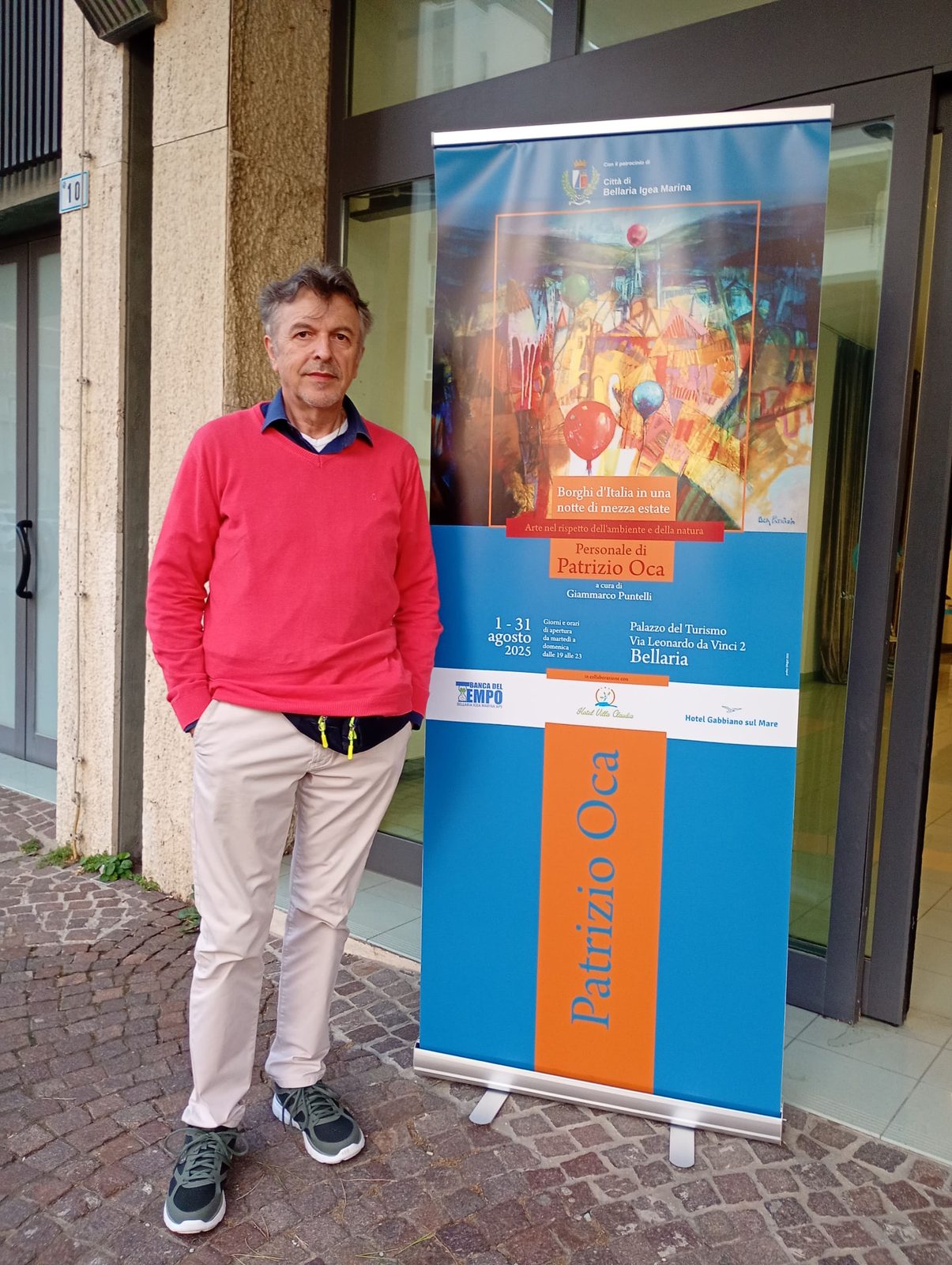 Patrizio Oca davanti al banner della mostra a Bellaria Igea Marina