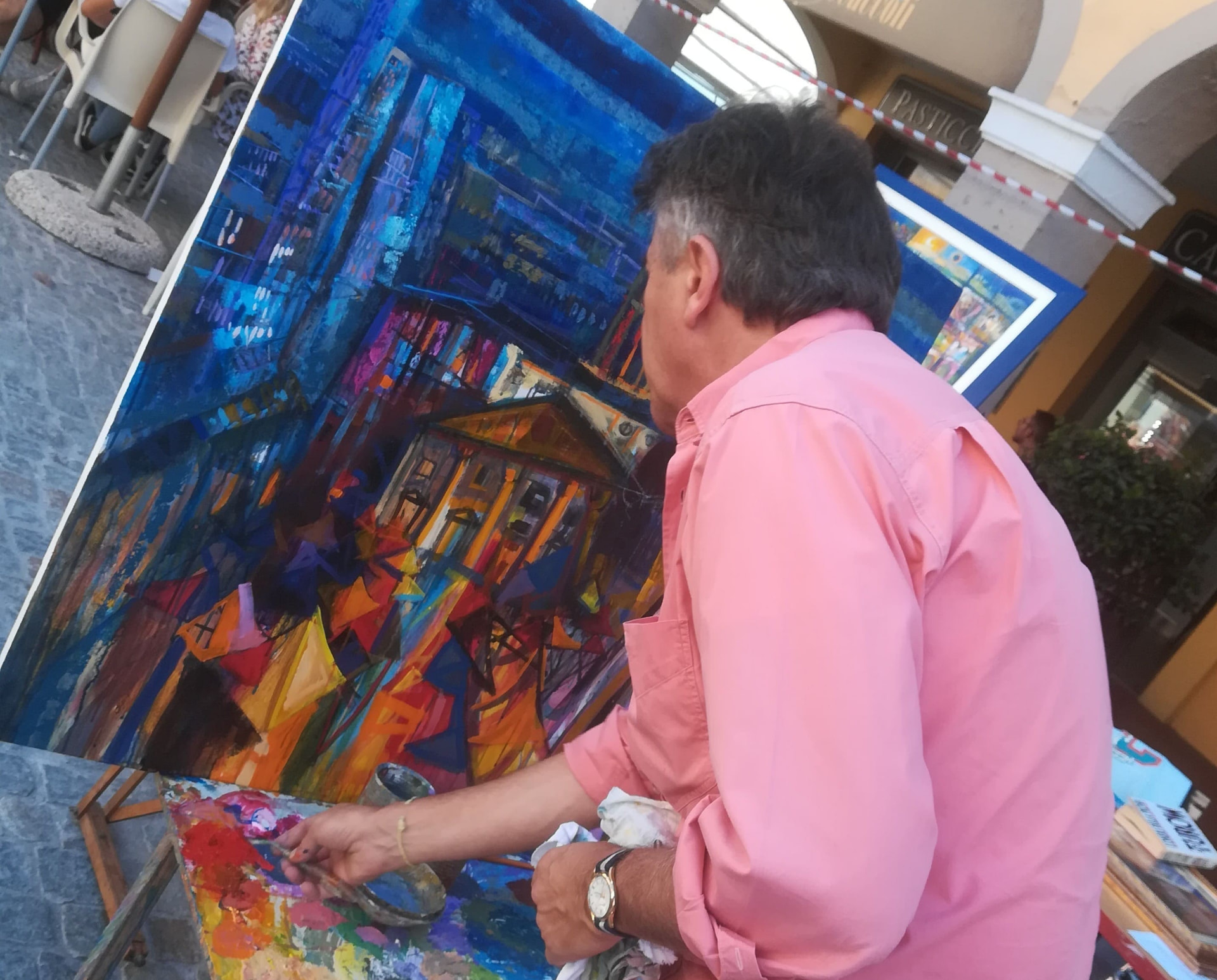 Patrizio Oca dipinge all'aperto davanti a un quadro blu