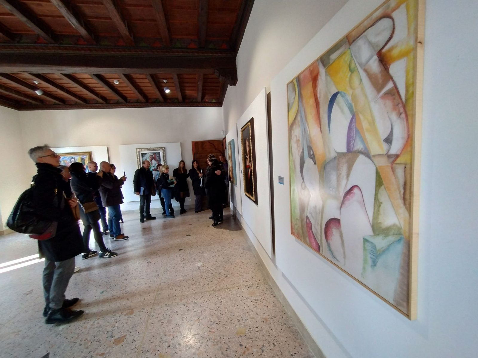 Visitatori ammirano le opere esposte nella sala della mostra